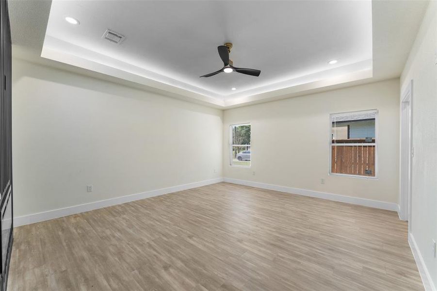 Unfurnished room featuring recessed lighting, ceiling fan, a tray ceiling, and light wood-style floors