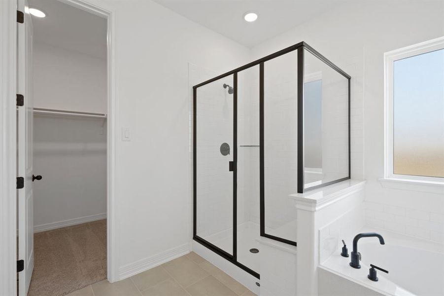 This additional view of your primary bathroom features tile flooring, fresh paint, walk-in shower, a separate garden tub, and a large walk-in closet.