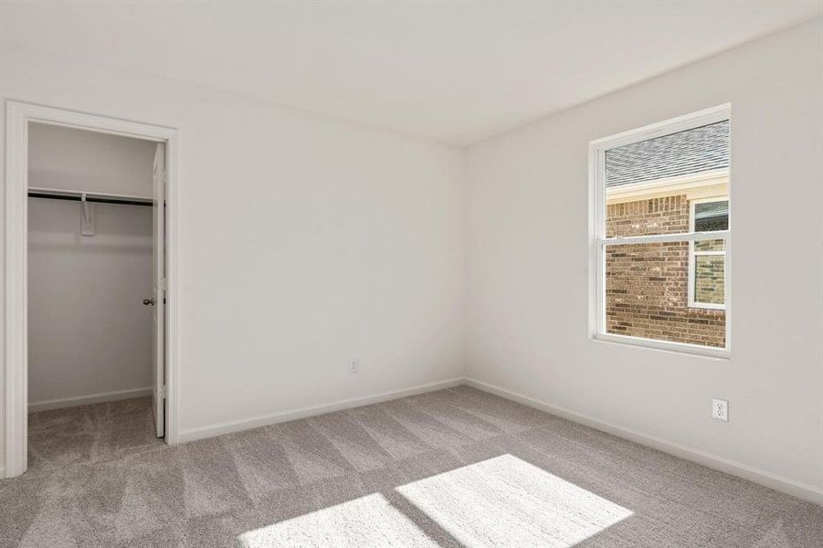 Unfurnished bedroom featuring a walk in closet and light colored carpet Unfurnished bedroom featuring a walk in closet and light colored carpet