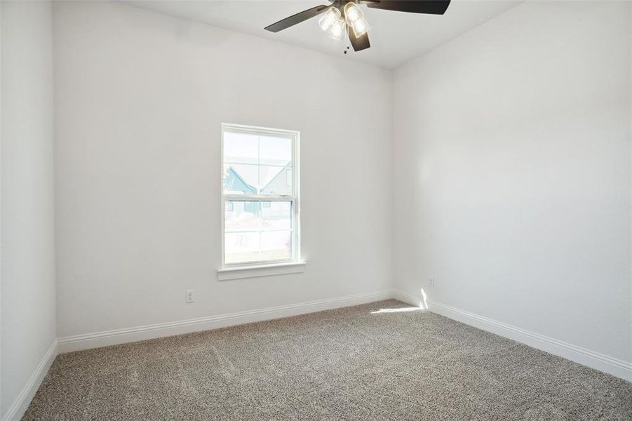 Carpeted spare room featuring ceiling fan