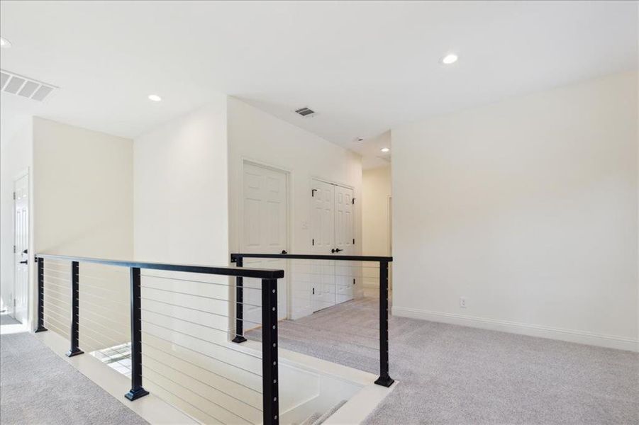 Hallway featuring light colored carpet