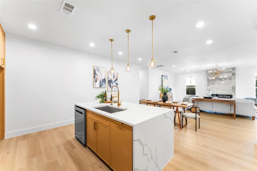 Kitchen featuring open floor plan, light wood-type flooring, light stone counters, and a chandelier