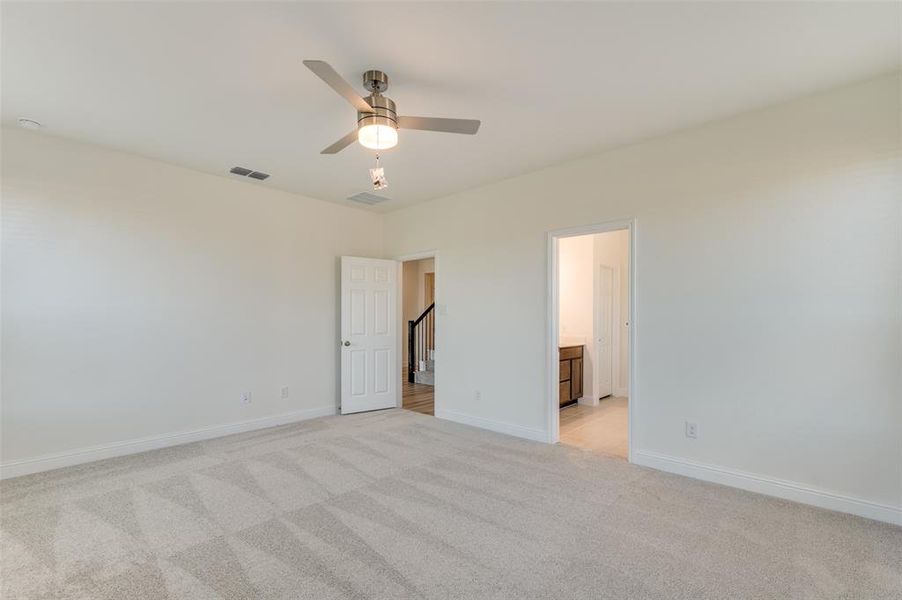 Unfurnished bedroom featuring light carpet, ceiling fan, and connected bathroom