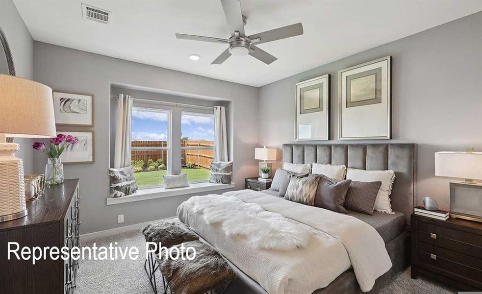 The bedroom features a window with a view of the backyard, a ceiling fan, and carpeted flooring