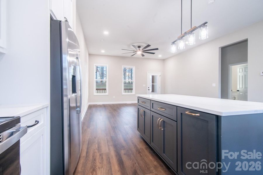 Open-concept kitchen featuring a large quartz island, contrasting cabinetry, and stainless steel appliances.