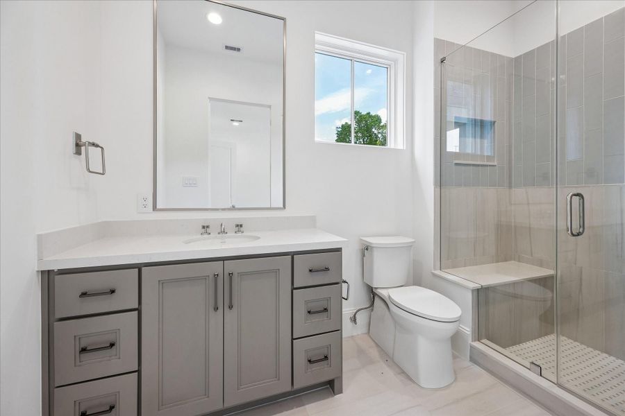 En-suite bathroom features a sleek, glass-encased shower, Quartz counters and additional counter and storage space.