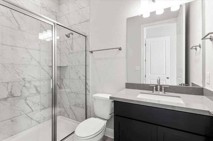 Bathroom with vanity, a marble finish shower, and a textured wall