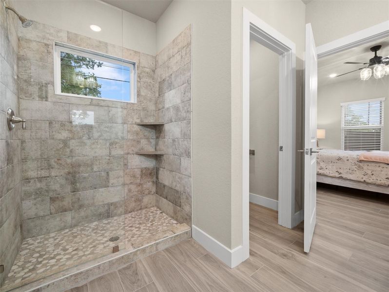 Ensuite bathroom featuring a stall shower, healthy amount of natural light, light wood-style flooring, a ceiling fan, and recessed lighting Ensuite bathroom featuring a stall shower, healthy amount of natural light, light wood-style flooring, a ceiling fan, and recessed lighting