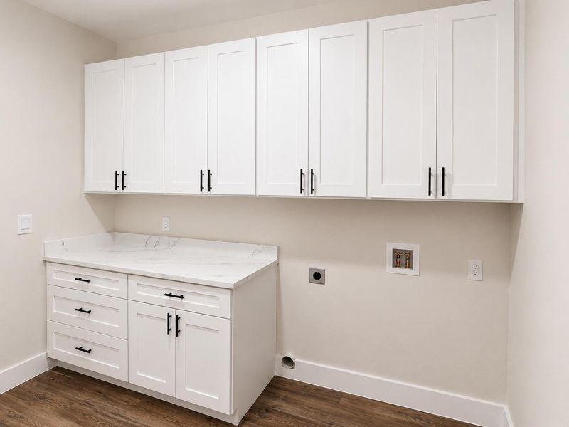 Ample storage and a sleek countertop define this well-appointed laundry space.