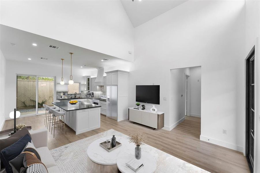 Living area with light wood-style flooring, recessed lighting, and a towering ceiling