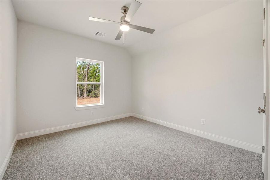 Empty room featuring light colored carpet, ceiling fan, and vaulted ceiling Empty room featuring light colored carpet, ceiling fan, and vaulted ceiling