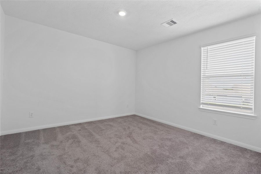 Well appointed secondary bedroom that features plush carpeting, neutral paint tones, recessed lighting, large window, and a generously sized closet.