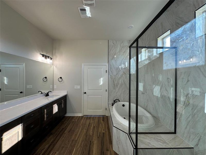 Bathroom with a bath, vanity, dark wood finished floors, and a marble finish shower Bathroom with a bath, vanity, dark wood finished floors, and a marble finish shower