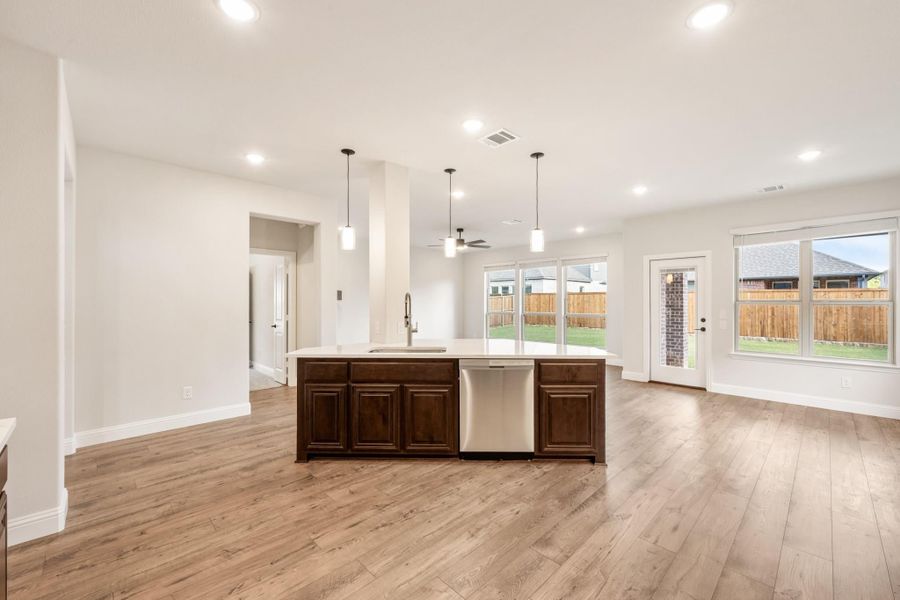 Open kitchen and living area with dark wood island, pendant lights, and hardwood floors