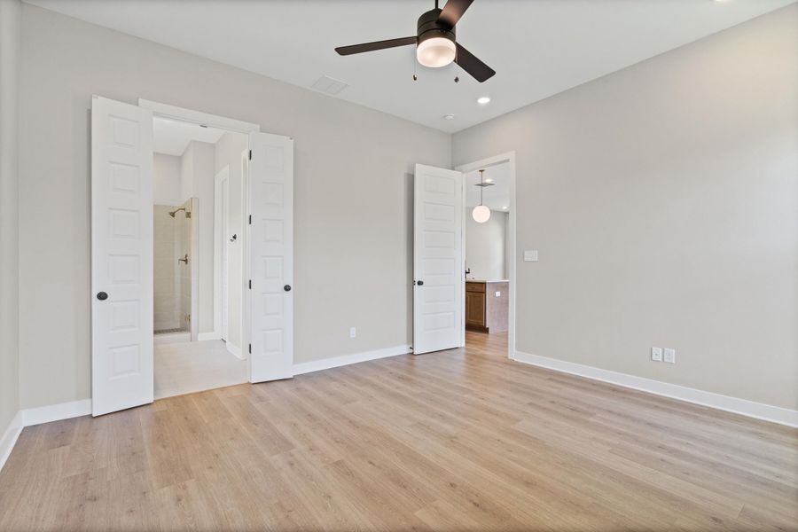 Spacious room featuring light wood-finish flooring, neutral wall paint, and white baseboards Spacious room featuring light wood-finish flooring, neutral wall paint, and white baseboards