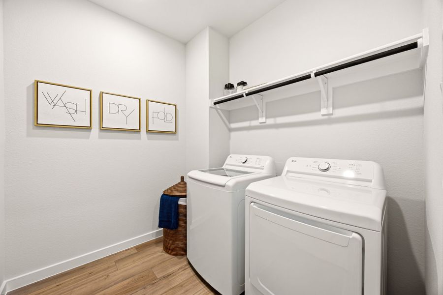 A laundry room with a white laundry machine and a white shelf.