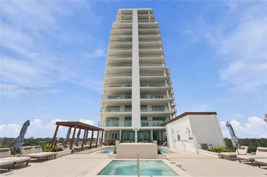 High-rise building exterior featuring tiered balconies with metal railings, elevated terrace level, tiled sundeck, built-in swimming pool, and custom pergola structure High-rise building exterior featuring tiered balconies with metal railings, elevated terrace level, tiled sundeck, built-in swimming pool, and custom pergola structure