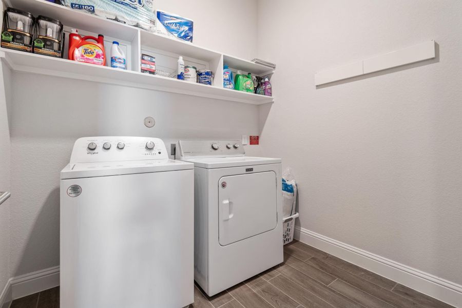 This laundry room features a washer and dryer with convenient shelving above for storage. The space is clean and functional, with tiled flooring and a neutral color palette. This laundry room features a washer and dryer with convenient shelving above for storage. The space is clean and functional, with tiled flooring and a neutral color palette.