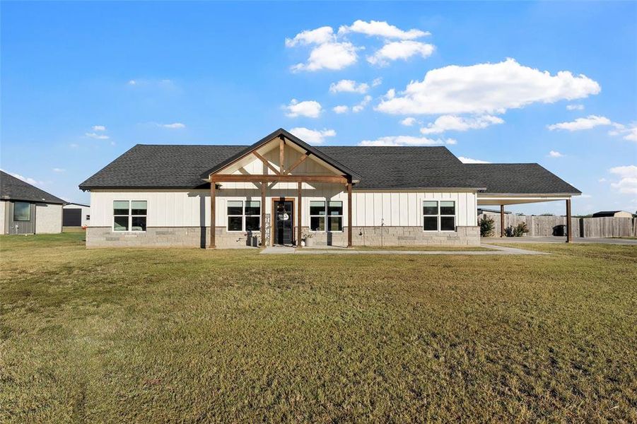 Back of house featuring a porch, a lawn, and roof with shingles
