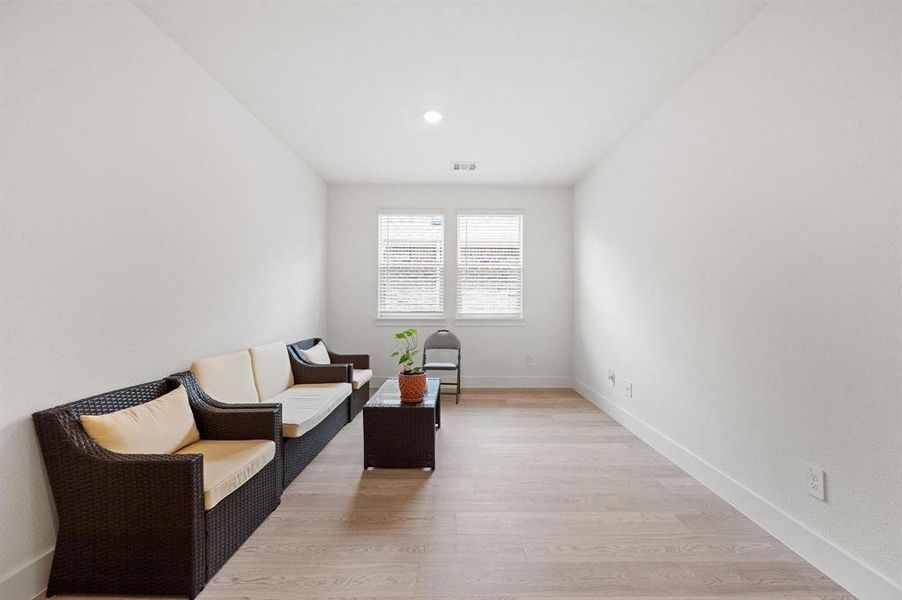 Spacious room with light wood-finish flooring, white baseboards, and neutral wall tones Spacious room with light wood-finish flooring, white baseboards, and neutral wall tones