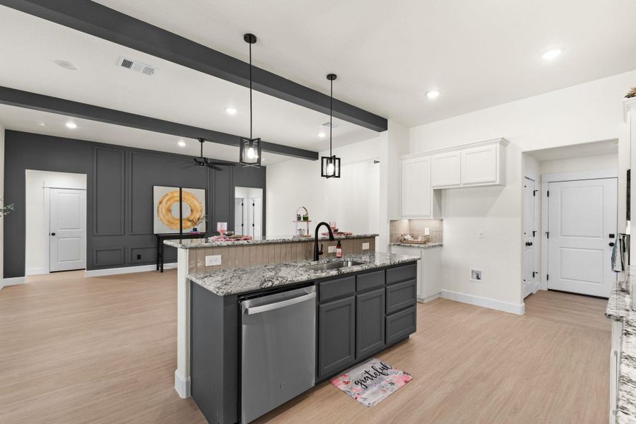 Kitchen with light stone counters, dishwasher, hanging light fixtures, light wood-style flooring, and ceiling fan