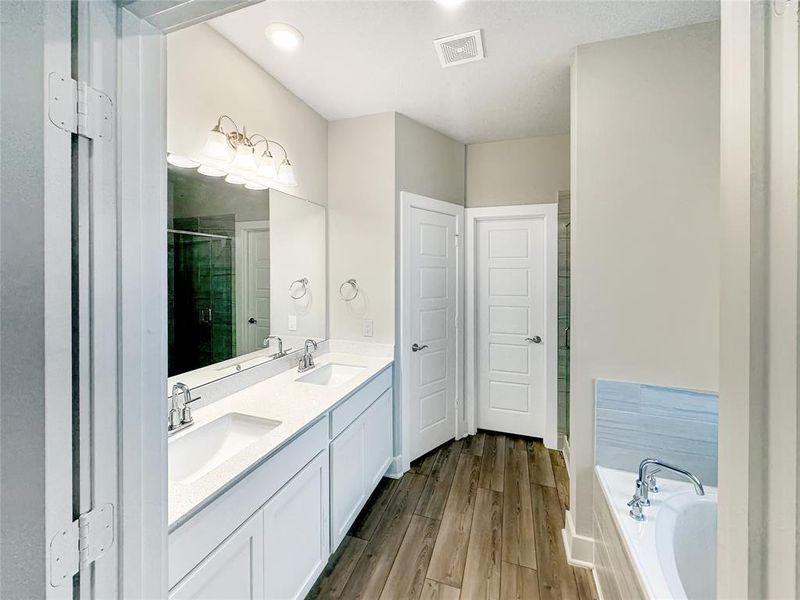 A clean, modern master bathroom with double vanity, large mirror, tiled shower, and a separate Tub .