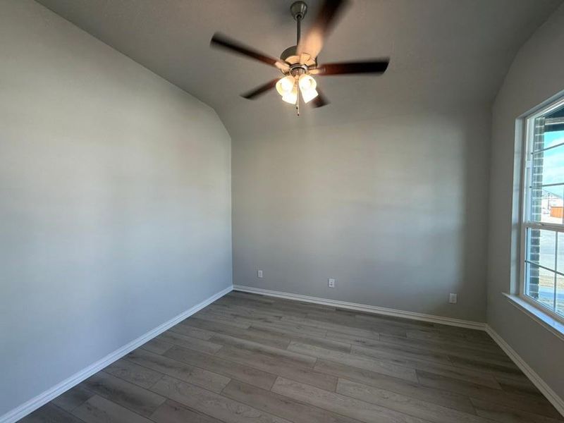 Empty room with vaulted ceiling, wood finished floors, and a ceiling fan Empty room with vaulted ceiling, wood finished floors, and a ceiling fan