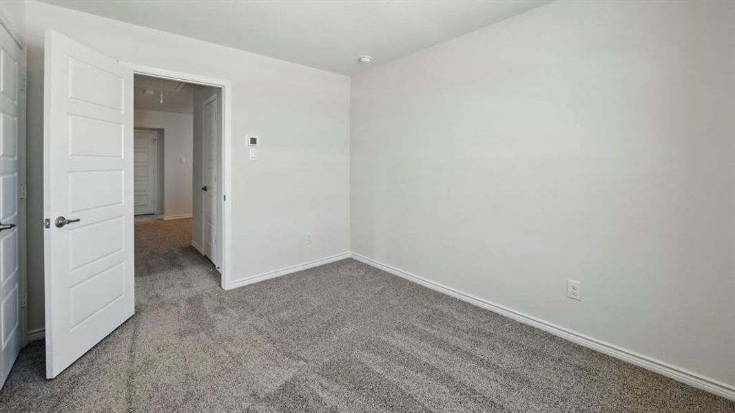 Carpeted empty room with attic access and baseboards
