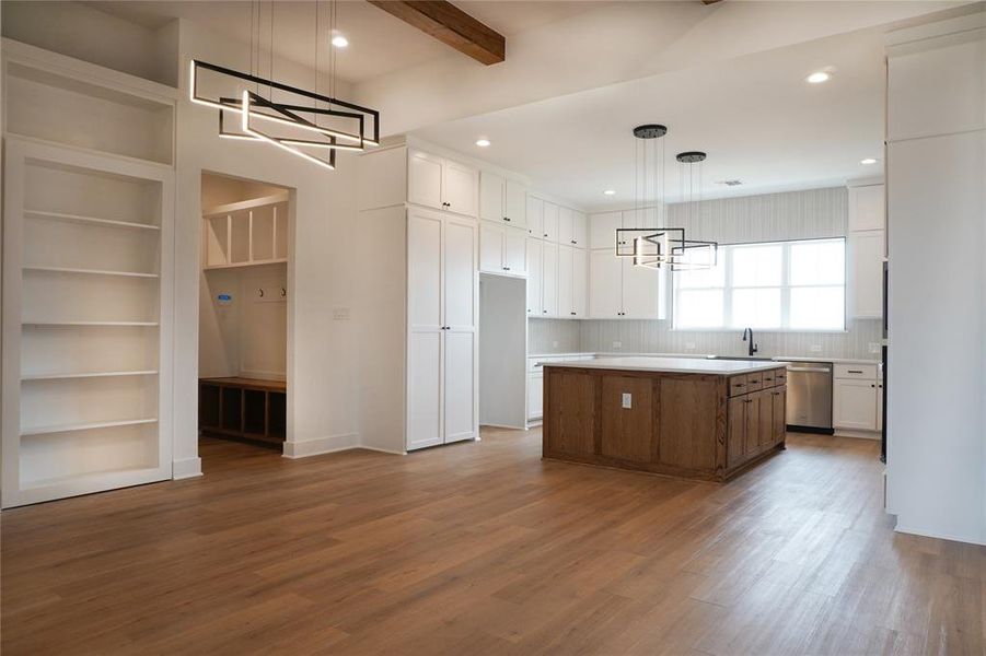 Kitchen with white cabinets, wood-type flooring, a center island, and decorative light fixtures