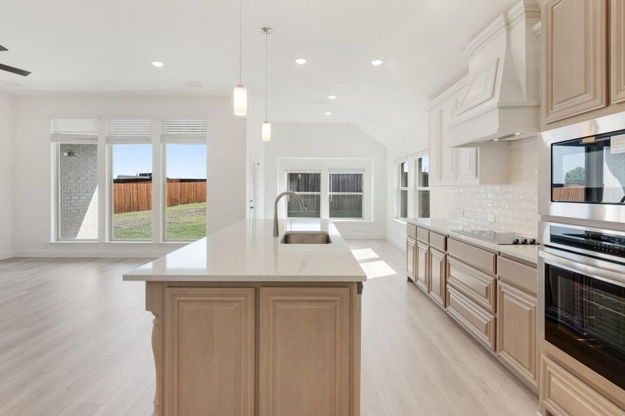 Kitchen with large center island, light wood cabinets, white countertops, and stainless steel appliances