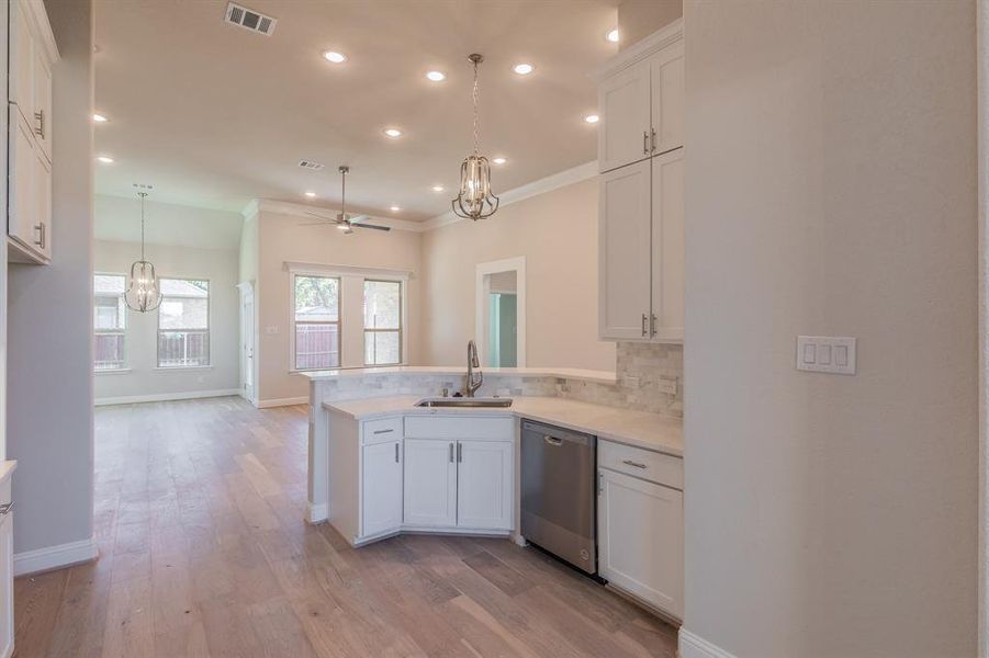 Kitchen with white cabinets, sink, stainless steel dishwasher, ceiling fan, and kitchen peninsula