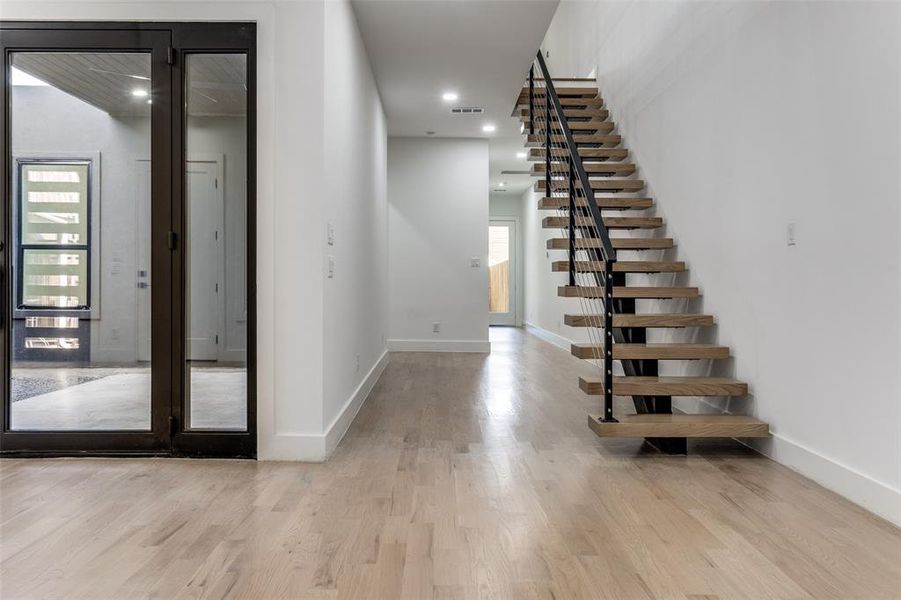Stairway with wood finished floors and recessed lighting