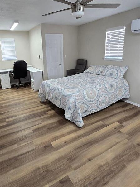 Bedroom featuring an office area, ceiling fan, and dark wood-type flooring