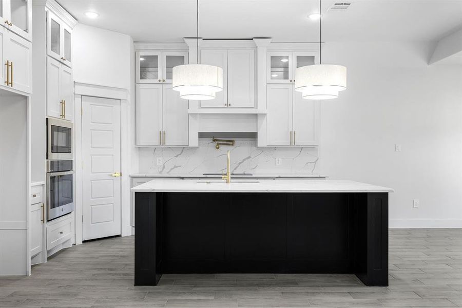 Kitchen with pendant lighting, a center island with sink, and white cabinetry