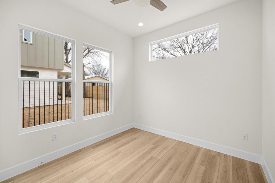 Bedroom #2 in the main floor features light wood-style floors, a ceiling fan, and recessed lighting
