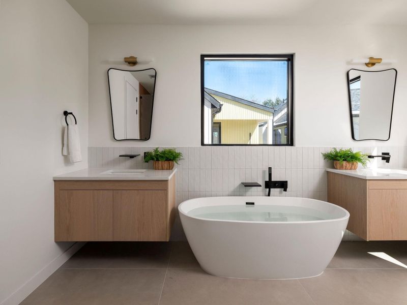 Bathroom with two vanities, a freestanding bath, tile walls, and light tile patterned floors