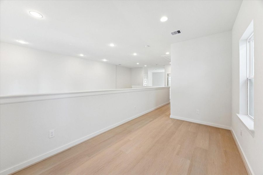 Alternate view highlights the study’s versatile layout, ample light from the windows, and the airy perspective looking down into the living area below.
