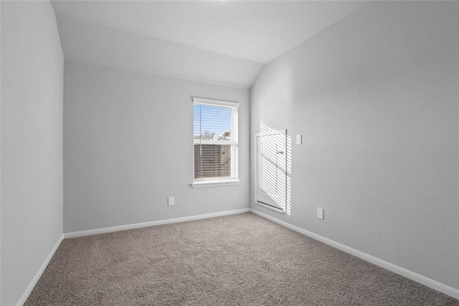 Step into this bright and airy secondary bedroom! It offers a tranquil space to unwind. The large window illuminates the room's sloped ceiling and neutral tones, creating a cheerful and airy environment.