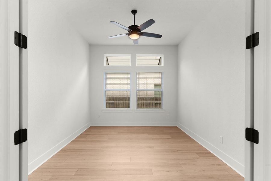 Bright room featuring light wood-finish flooring, crisp white walls, and a contemporary ceiling fan with integrated lighting Bright room featuring light wood-finish flooring, crisp white walls, and a contemporary ceiling fan with integrated lighting