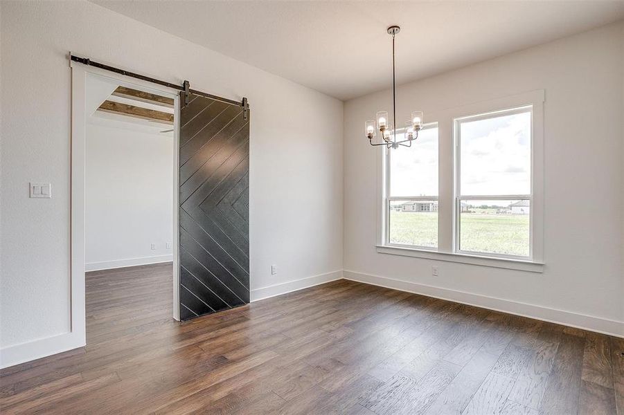 Unfurnished room with a notable chandelier, dark hardwood / wood-style flooring, and a barn door