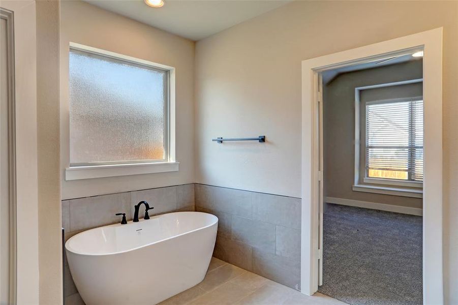 Bathroom with a freestanding bath, tile walls, recessed lighting, and tile patterned flooring