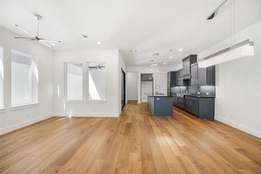 Kitchen featuring dark countertops, decorative backsplash, open floor plan, a sink, and light wood-type flooring