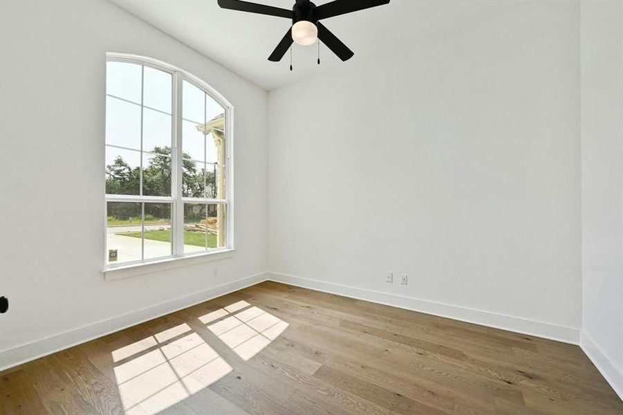 Empty room with wood finished floors and a ceiling fan Empty room with wood finished floors and a ceiling fan