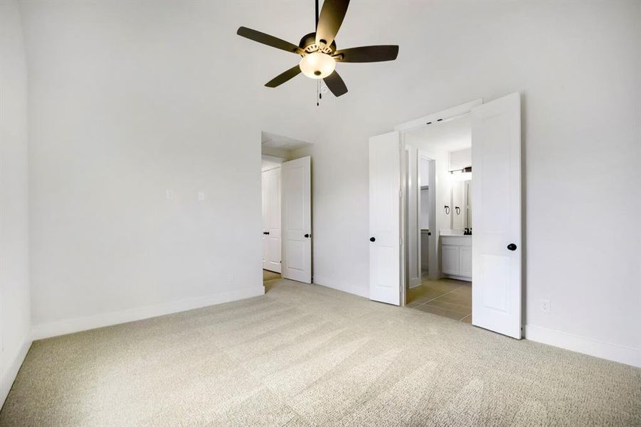 Carpeted interior space featuring a ceiling fan with integrated lighting, white walls, and white trim Carpeted interior space featuring a ceiling fan with integrated lighting, white walls, and white trim