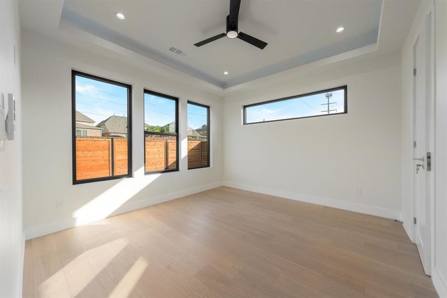Spare room with light wood-style floors, a tray ceiling, ceiling fan, and recessed lighting Spare room with light wood-style floors, a tray ceiling, ceiling fan, and recessed lighting