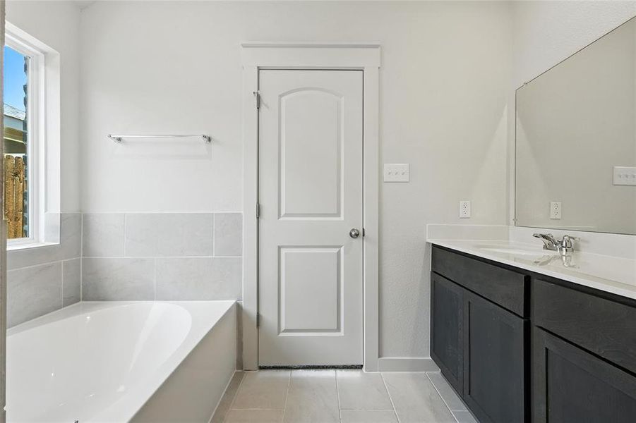 Full bathroom featuring vanity, a bath, and light tile patterned floors