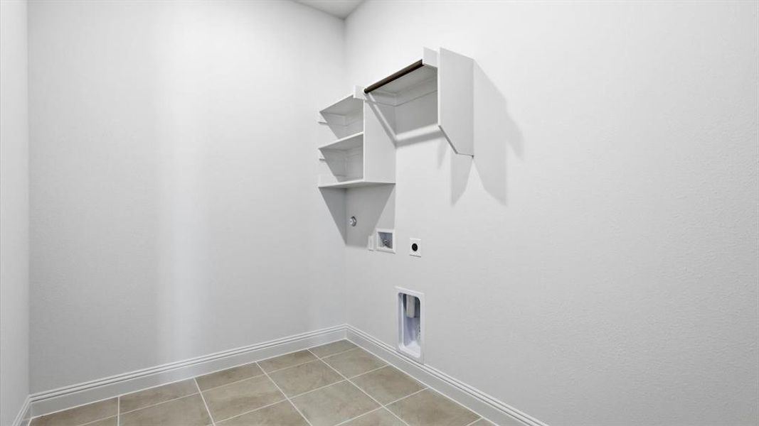 Utility space featuring neutral-toned tile flooring, white baseboards, and bright white walls
