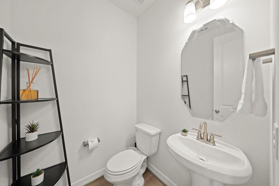 Located downstairs, a spacious half-bathroom features a sleek pedestal sink.