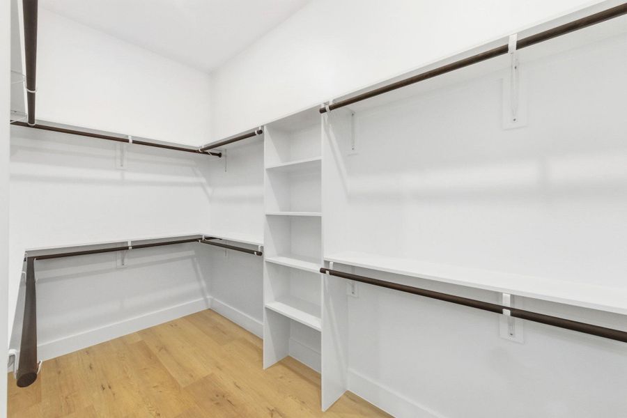 Spacious closet with light wood-style flooring Spacious closet with light wood-style flooring