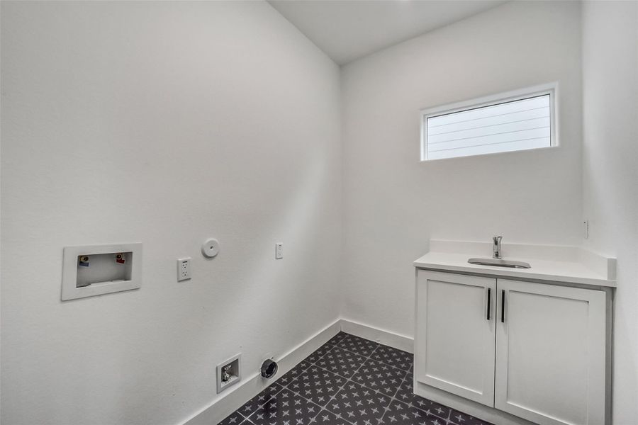 Spacious laundry room with dedicated washer and dryer connections, utility sink, storage cabinetry, and natural light. Located in the 2nd floor.